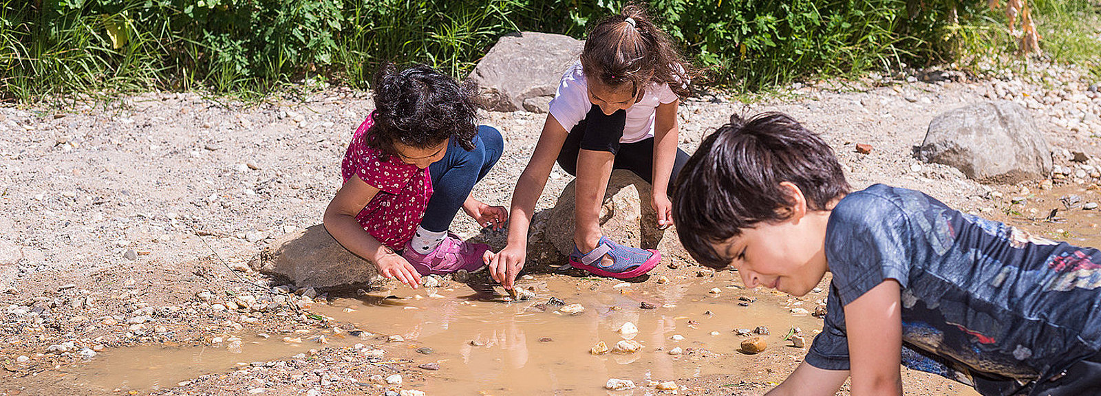Kinder forschen im Wasserlauf des Naturerfahrungsraums auf dem Tempelhofer Feld
