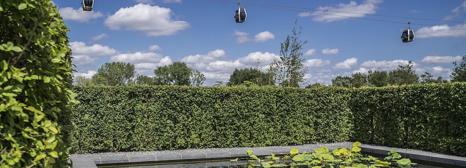 Über einem Wasserbecken mit Seerosen schwebt die Grün Berlin Seilbahn in den Gärten der Welt